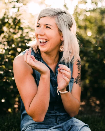 Woman laughing freely outdoors, representing the emotional freedom and ease somatic coaching and Rapid Coherence Integration can bring after releasing a stuck pattern